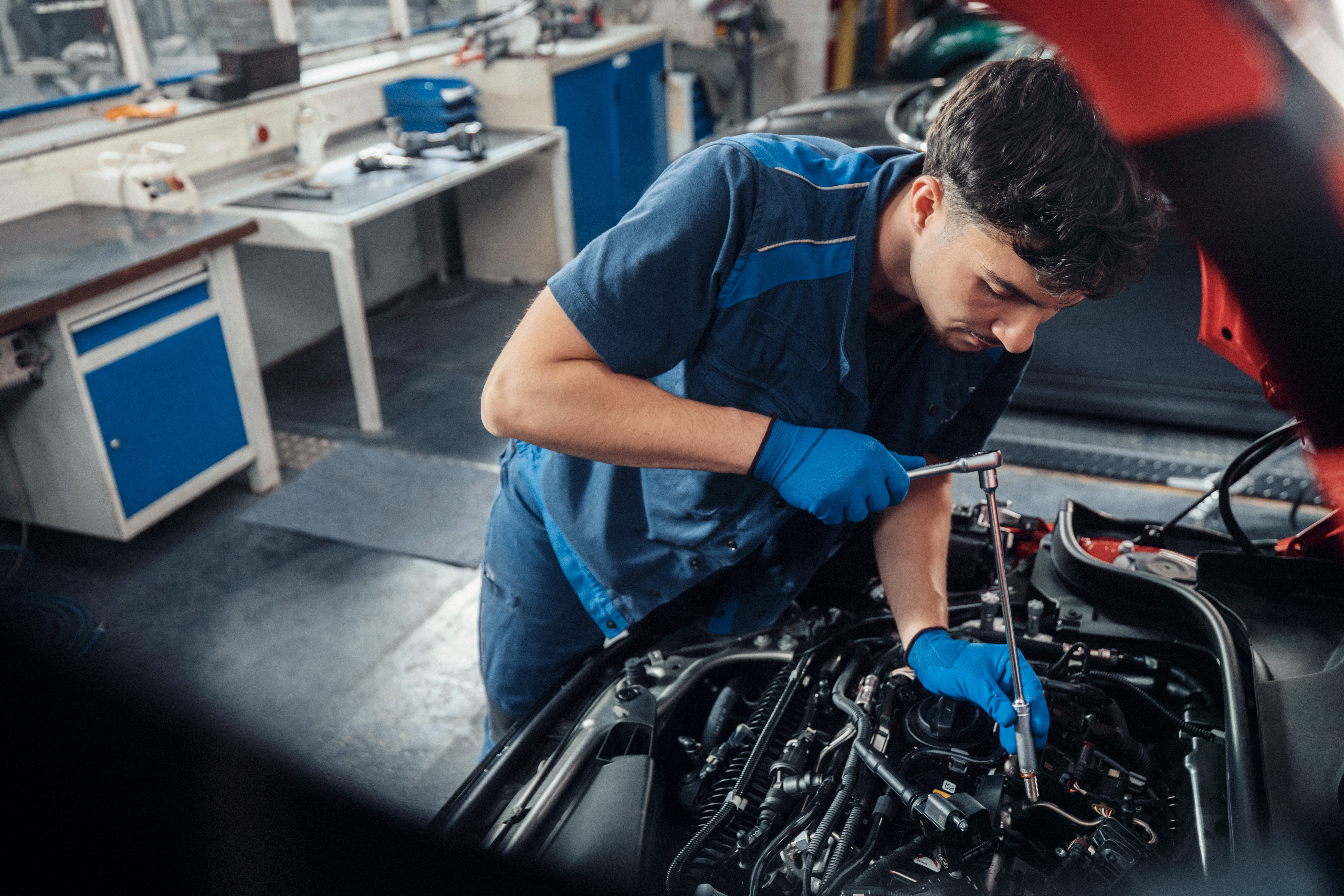 Técnico MINI a trabalhar no motor de um veículo com o capô aberto, dentro de uma oficina.